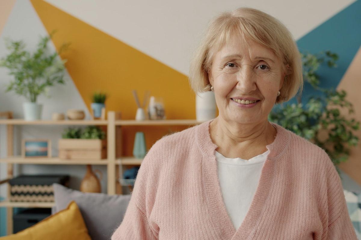 Bewoonster van een woonzorglocatie, glimlachend in een lichte woonkamer
